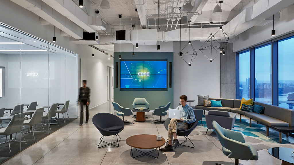 A person standing in a room with a projector screen and chairs.