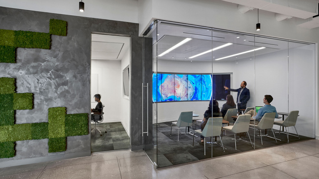 A group of people sitting in a room with a large screen.