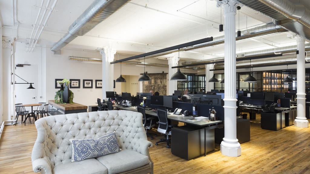A room with a couch and a table with a computer on it.