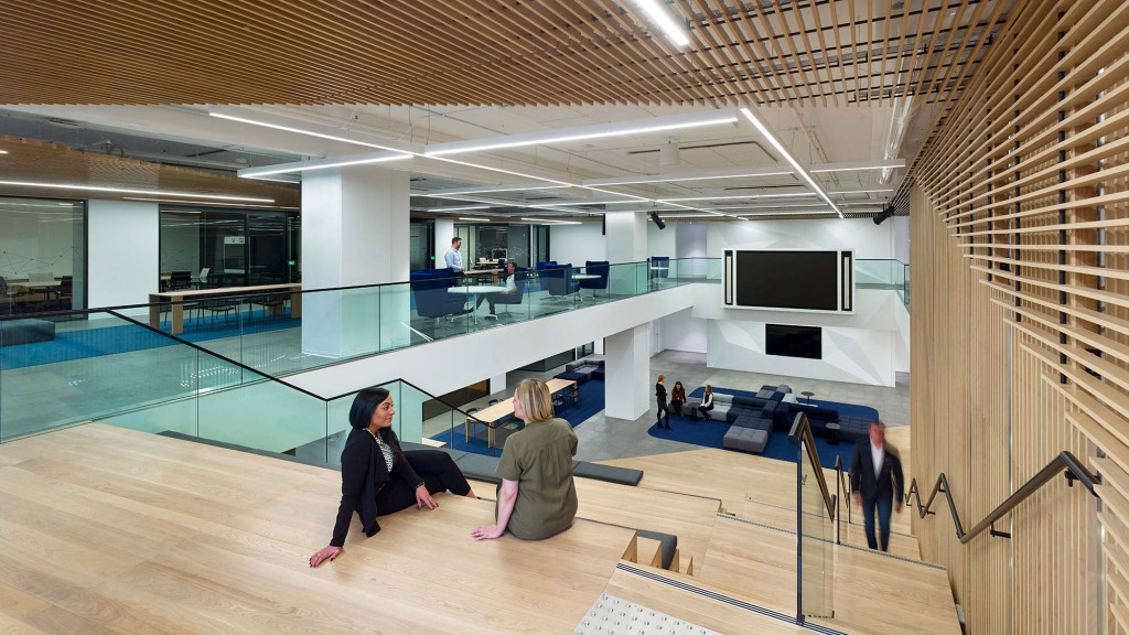 A group of people sitting on a deck in a large room.