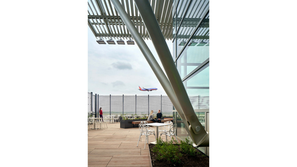 A group of people sitting at a table on a deck with a large sailboat in the background.
