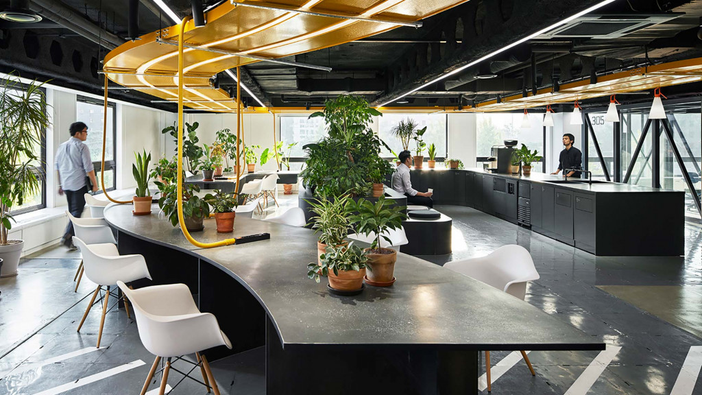 A group of people in a room with plants and chairs.