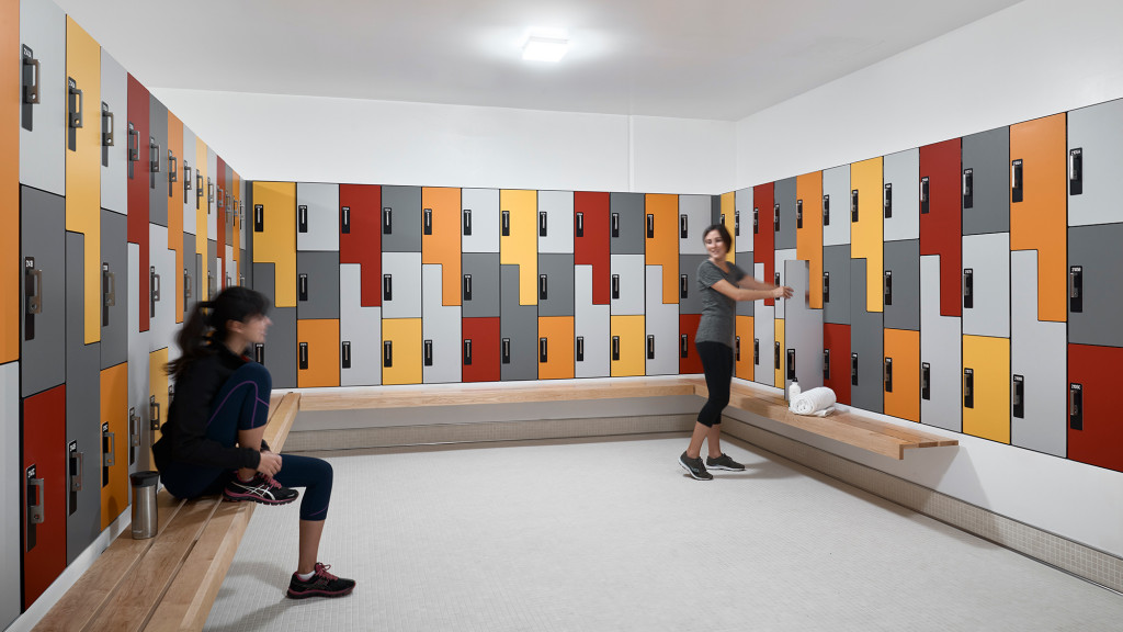 A person sitting on a bench next to a person standing in a room with red and yellow walls.