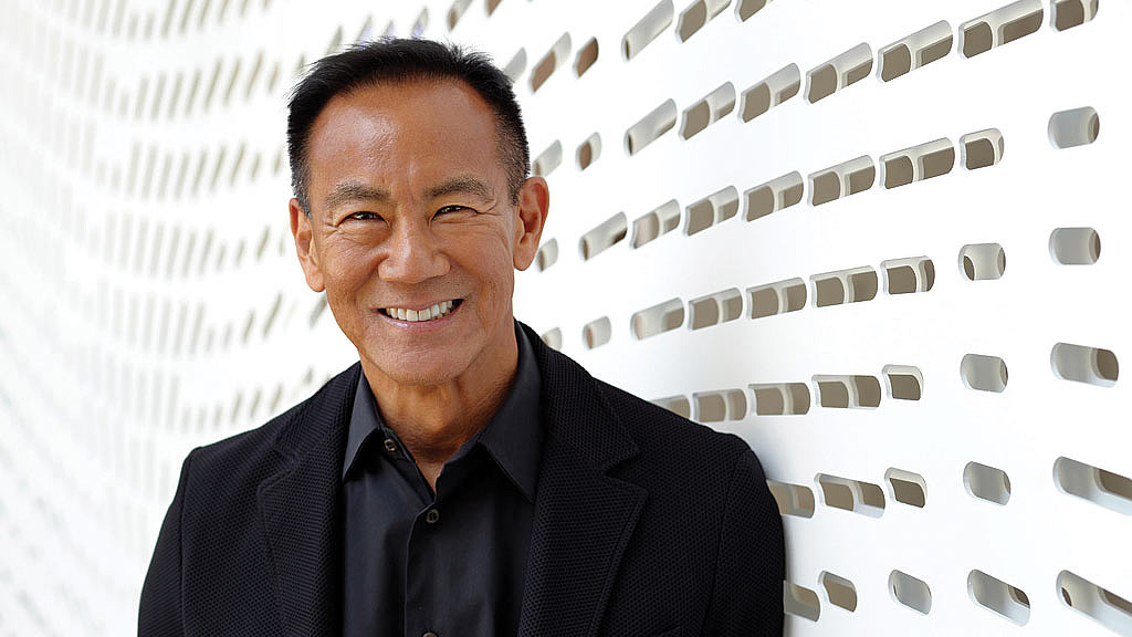 A man smiling in front of a building.