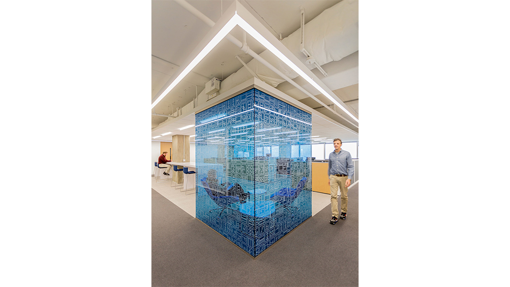 A person standing next to a large blue cage with birds inside.