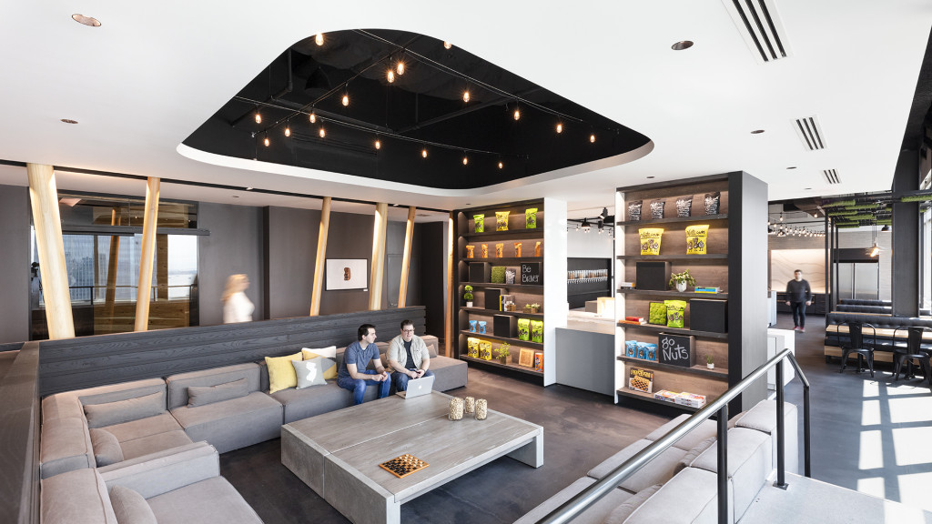 A couple of people sitting on a couch in a large room with a bar and a large glass.