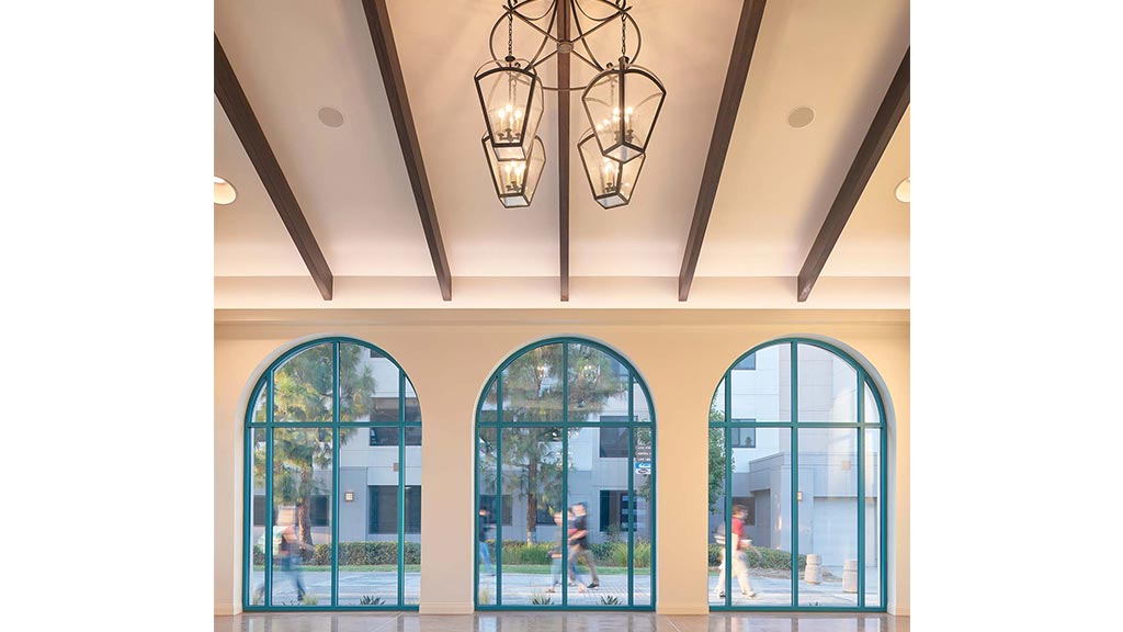 A chandelier from a ceiling in a room with windows.