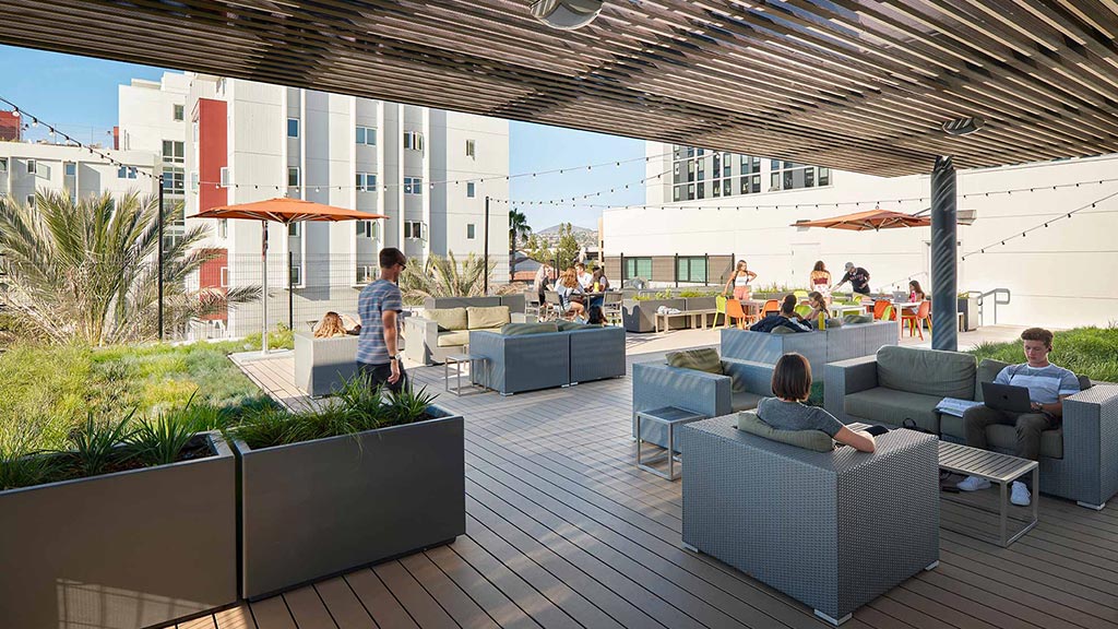 A group of people sitting on a deck with a large glass roof.