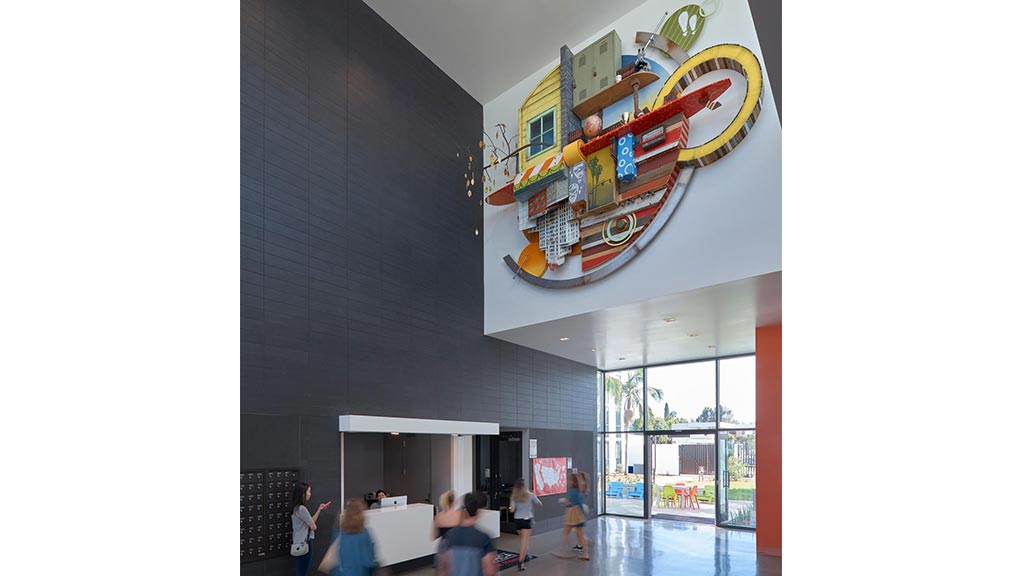 A group of people walking around a building with a sign on the ceiling.