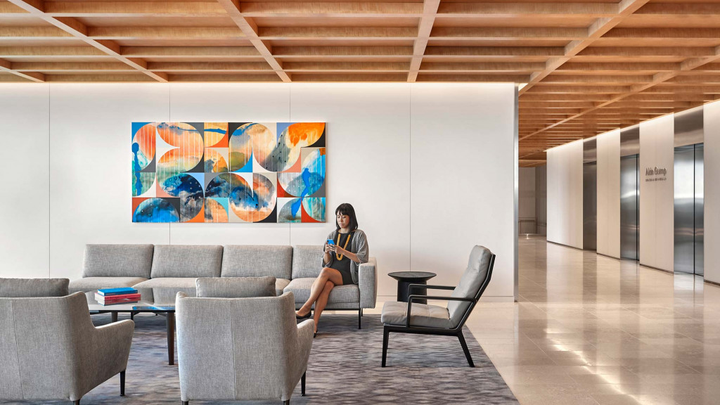 A person sitting on a chair in a room with a large painting.