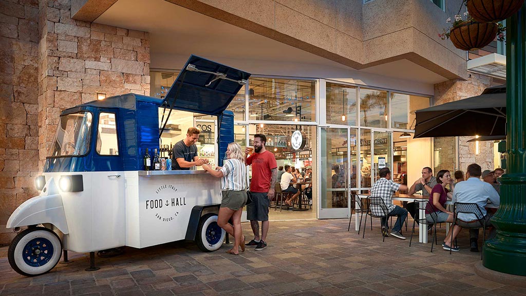 A small white vehicle with a blue top parked outside a building.