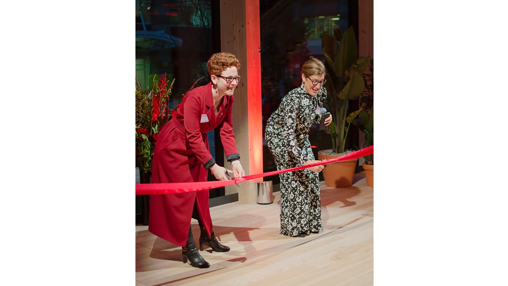 A man and woman holding a red ribbon.