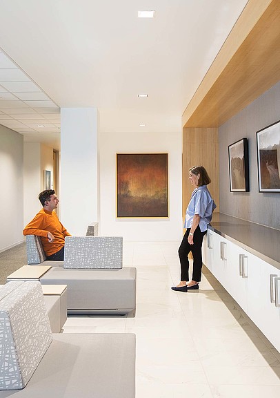 A man and a woman looking at a painting on the wall.