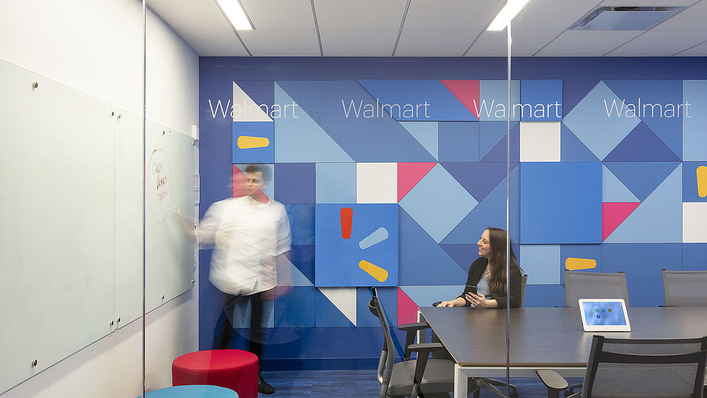 A man and woman in a room with a large blue wall.