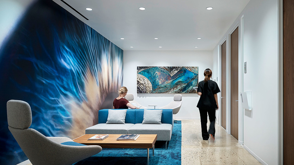 A woman standing in a room with a man sitting at a table.