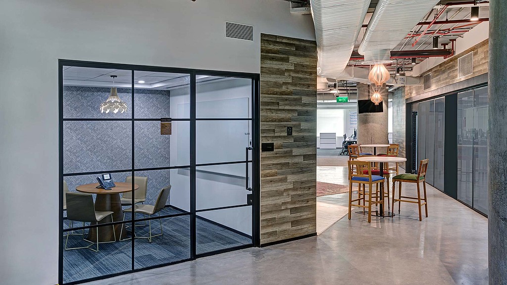A room with a glass door and a table with chairs and a brick wall with a brick wall.