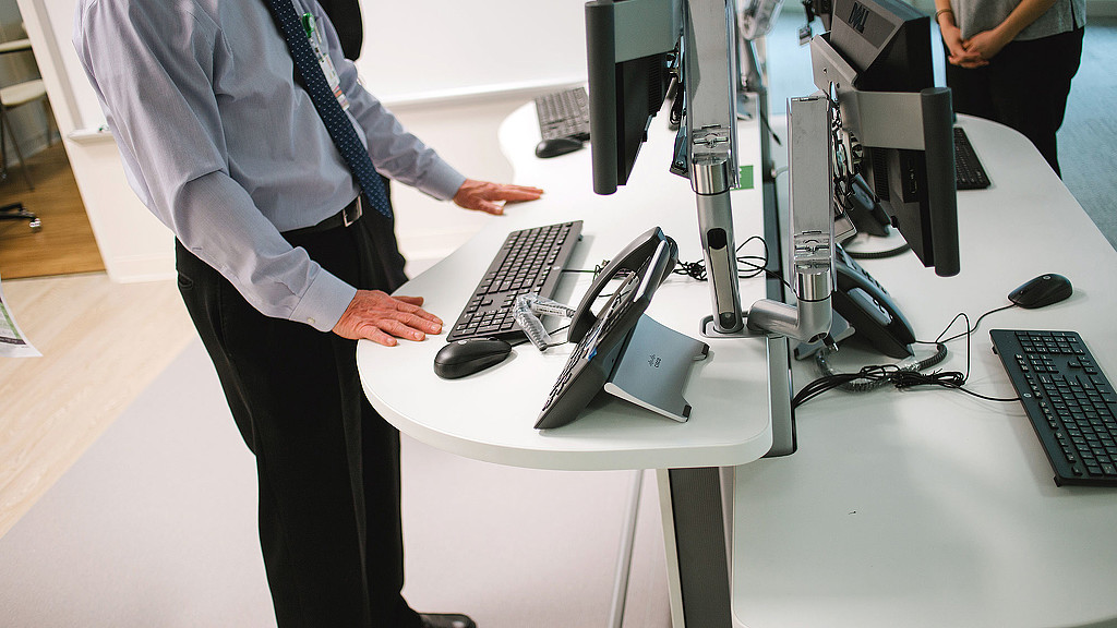 A person standing in front of a desk with computers.