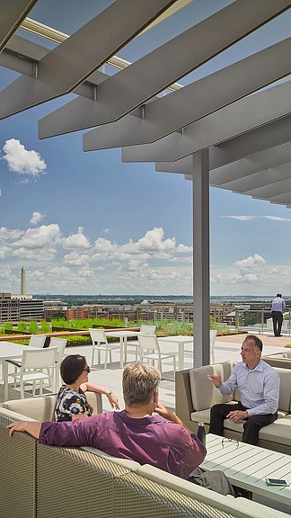 A group of people sitting on a deck looking out over a city.