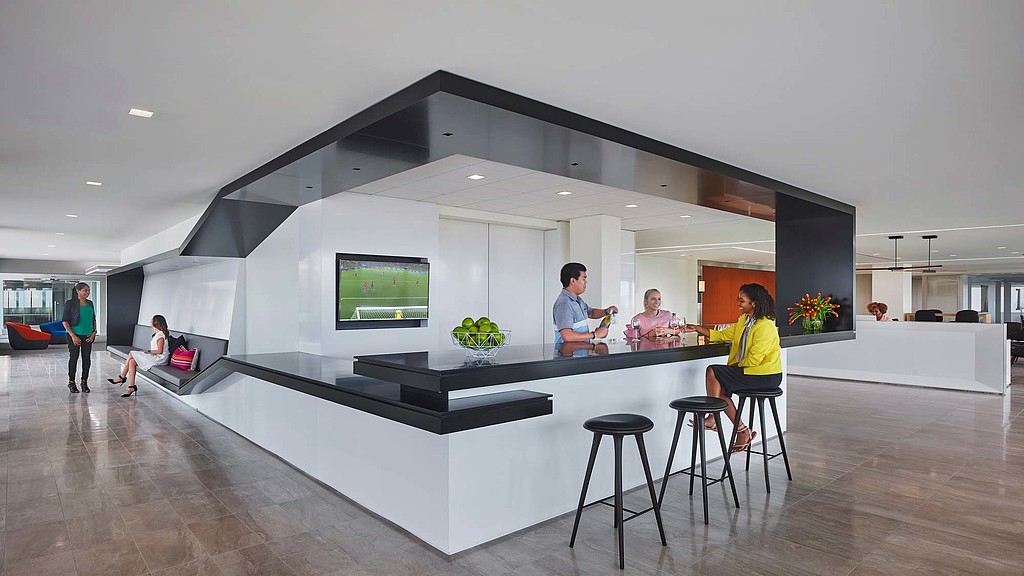 A group of people sitting at a table in a room with a tv.