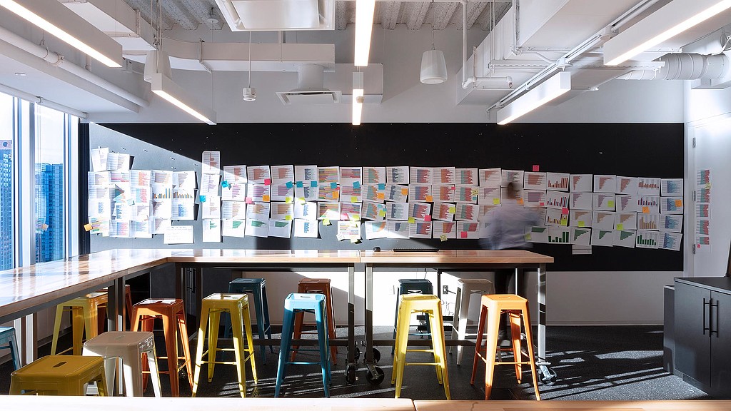 A room with stools and a wall of posters.