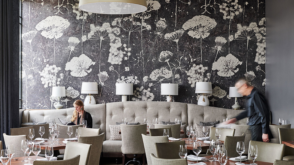 A man and woman sitting at a table with wine glasses.
