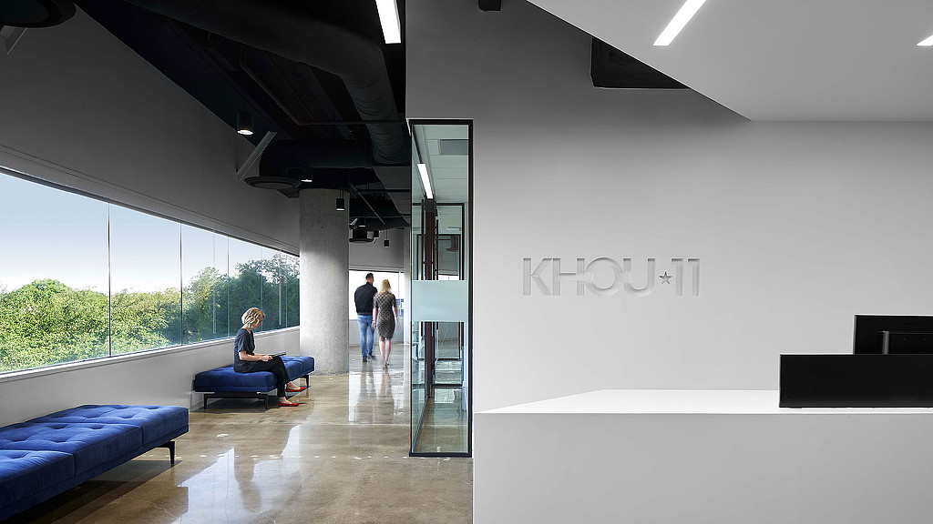 A person sitting on a chair in a room with a large glass door.