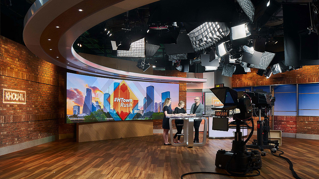 A group of people sitting at a table in front of a large screen.