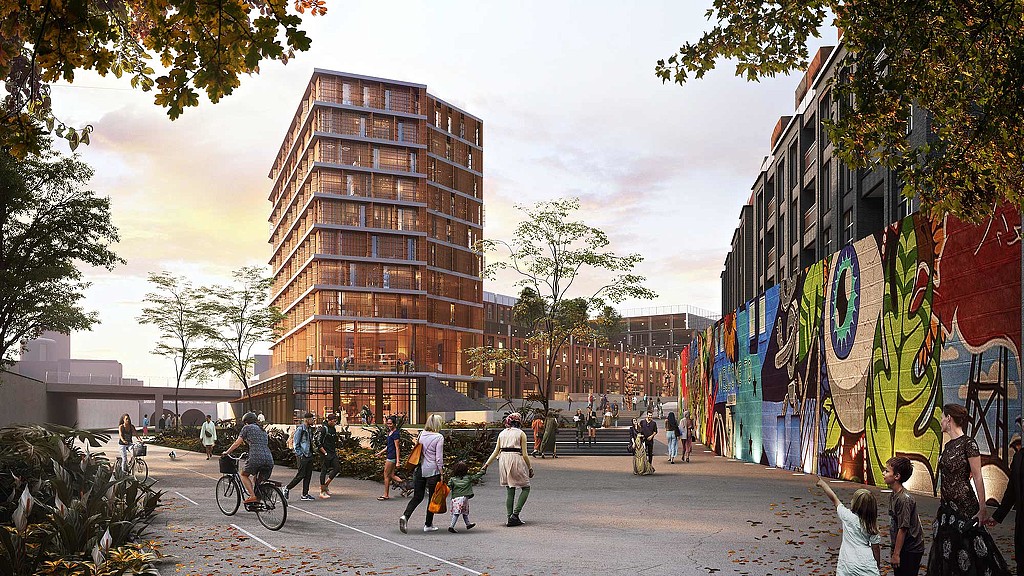 A group of people walking on a street with buildings on either side.