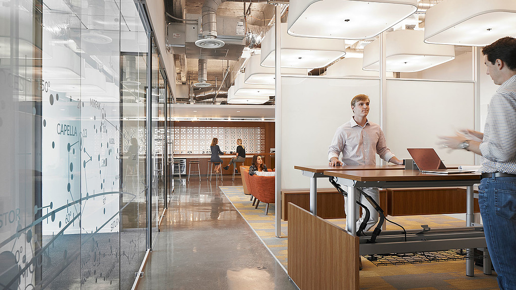 A person standing in front of a glass wall with a laptop on it.