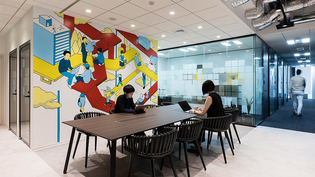 A man and woman sitting at a table with a laptop.