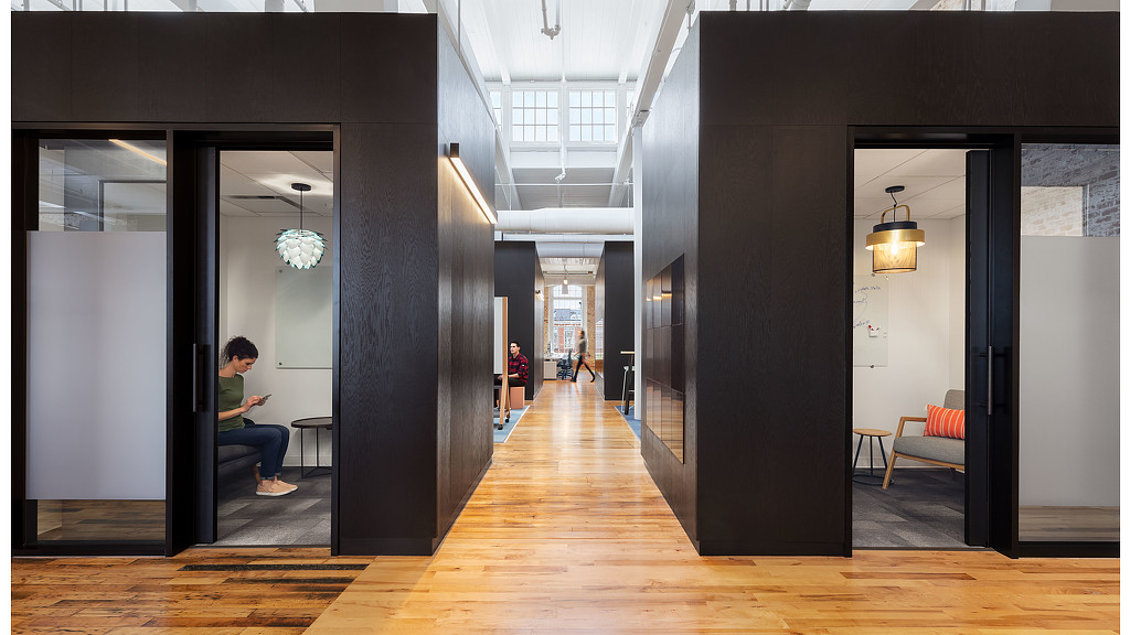 A person sitting on a bench in a room with a wood floor.