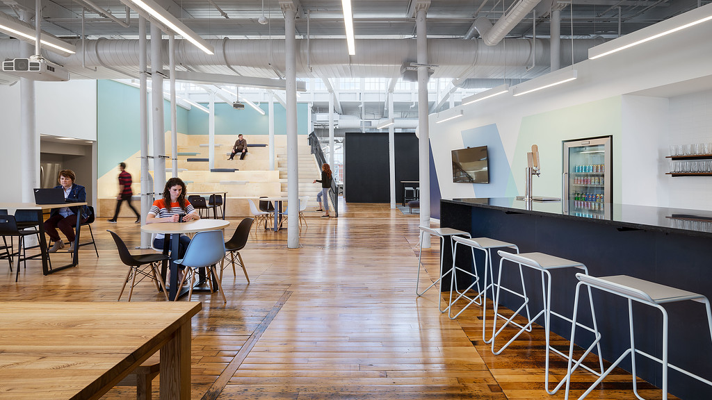 A group of people sitting at tables in a room with white walls.