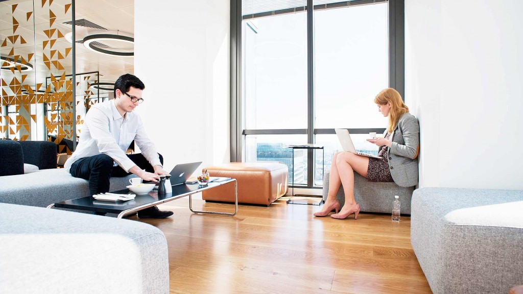 A man and a woman sitting on a couch with a laptop.