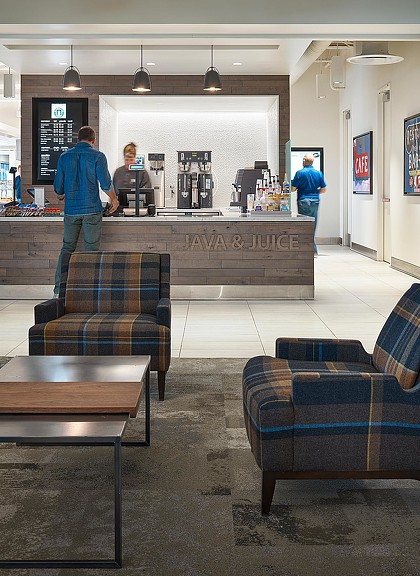 A group of people standing in a room with a bar and chairs.
