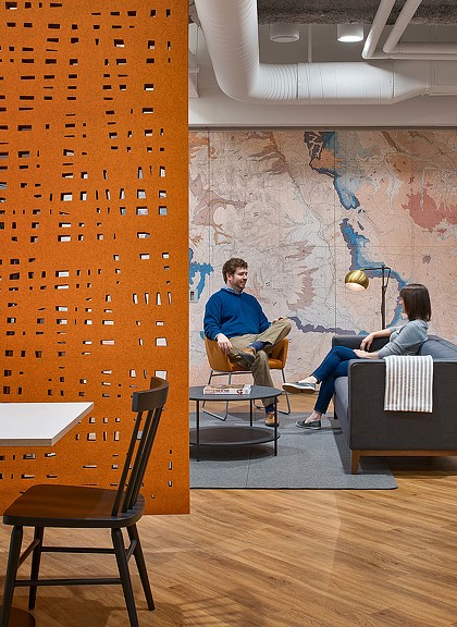 A man and a woman sitting on a couch in front of a painting.