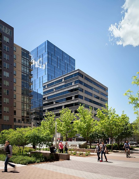 A group of people walking around a park in front of a building.