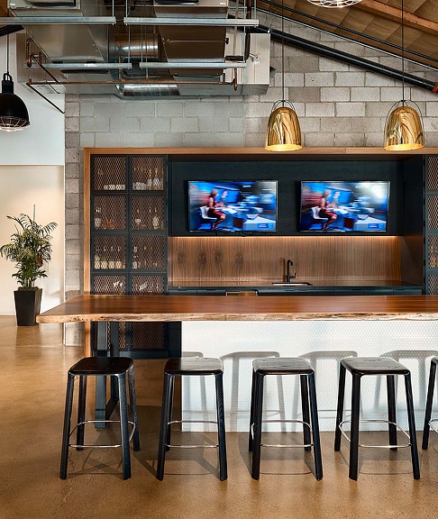 A bar with stools and a tv on the wall.