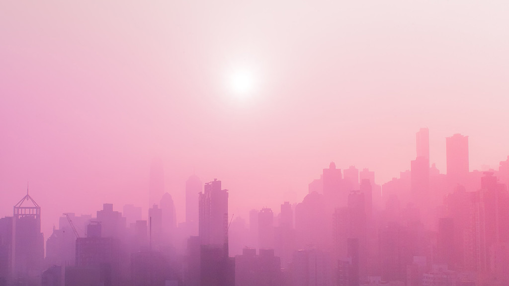 A city skyline with the sun shining.