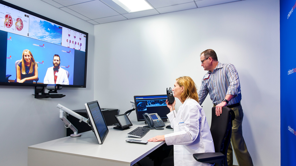 A man and a woman talking to each other at a desk with computers.