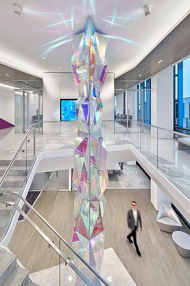 A person walking in a large room with a tall glass tower.