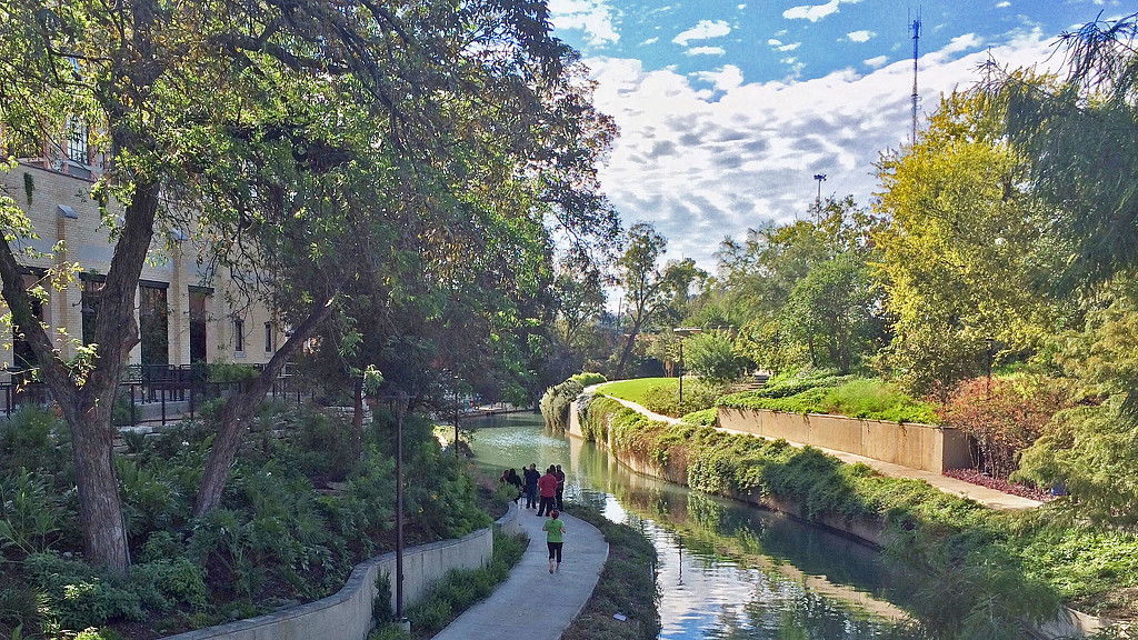 A group of people walking on a path by a river.