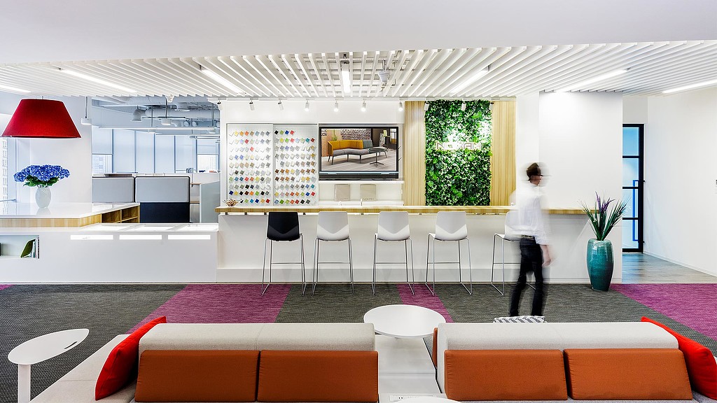 A person standing in a room with a large screen and chairs.