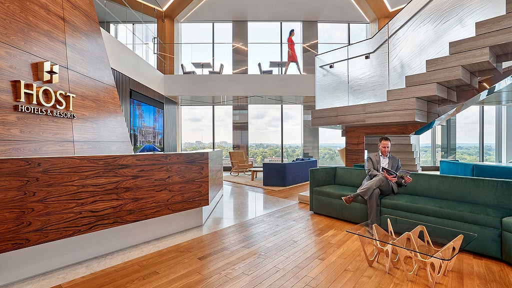 A person sitting on a couch in a room with a large glass wall.
