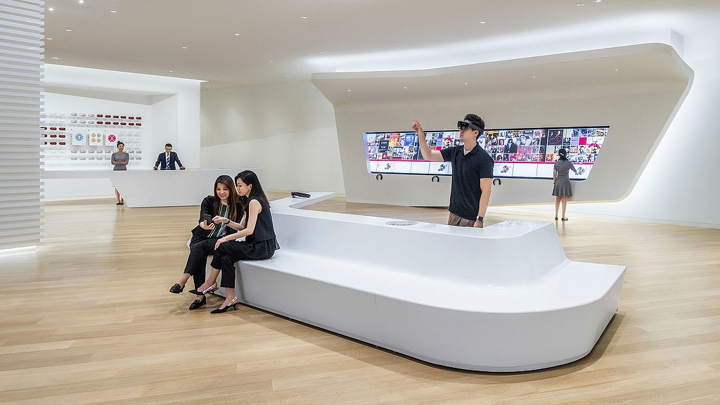 A group of people sitting on a couch in a room with a large screen.