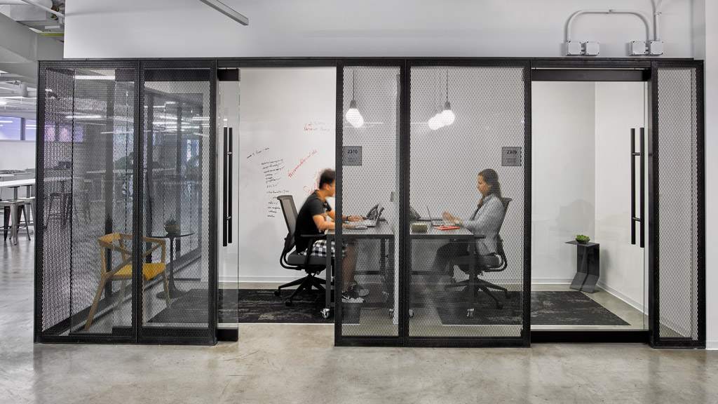 A couple of people sitting at a table in a room with glass doors.