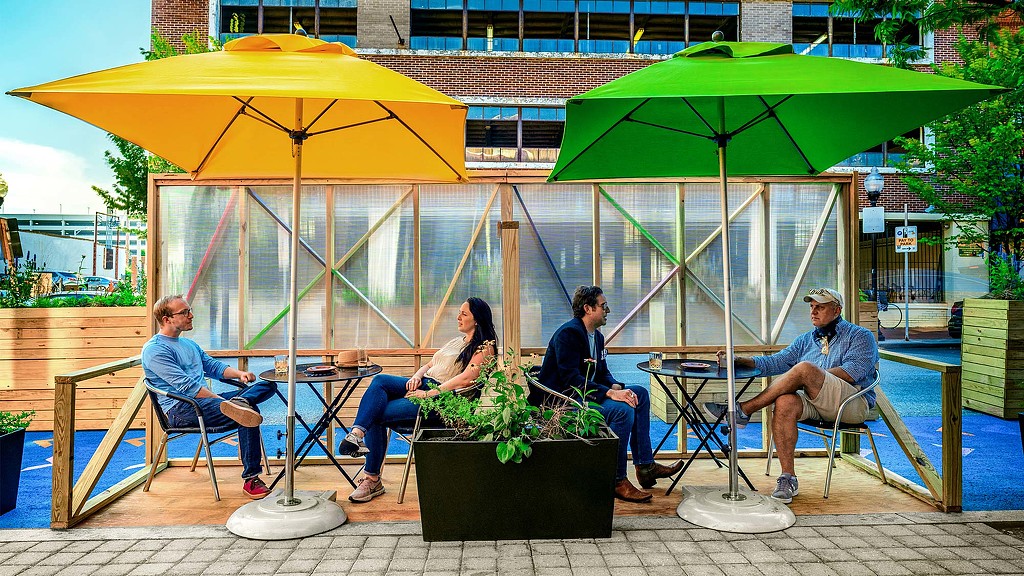 People sitting at a table under umbrellas.