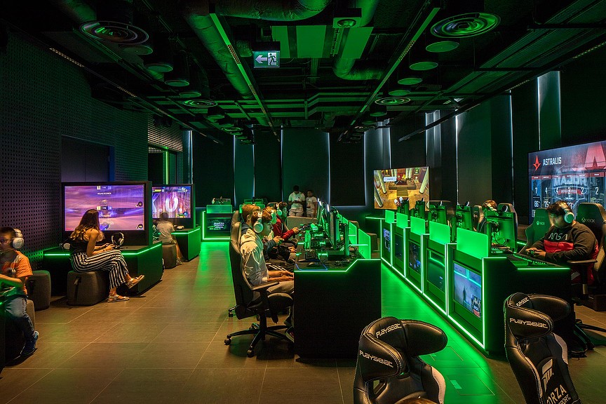 People sitting in a room with many screens and a large screen.