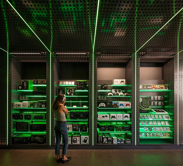 A person standing in front of a green display of electronic equipment.