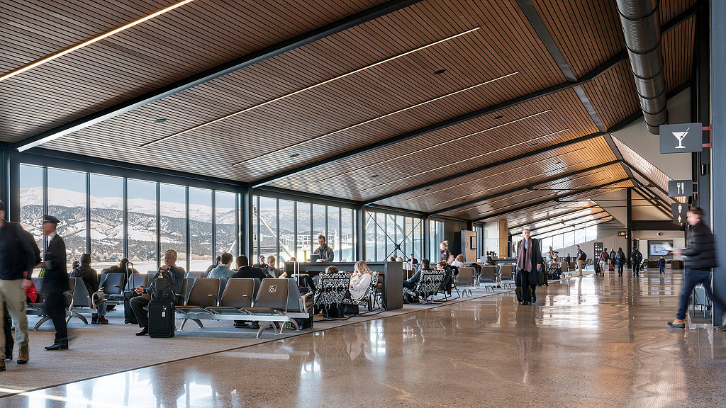 A group of people sitting in chairs in a large room with large windows.