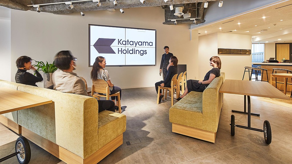 A group of people sitting in a room with a projector screen.